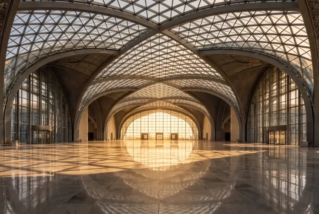 Golden-hour light through a vaulted glass roof and curtain wall