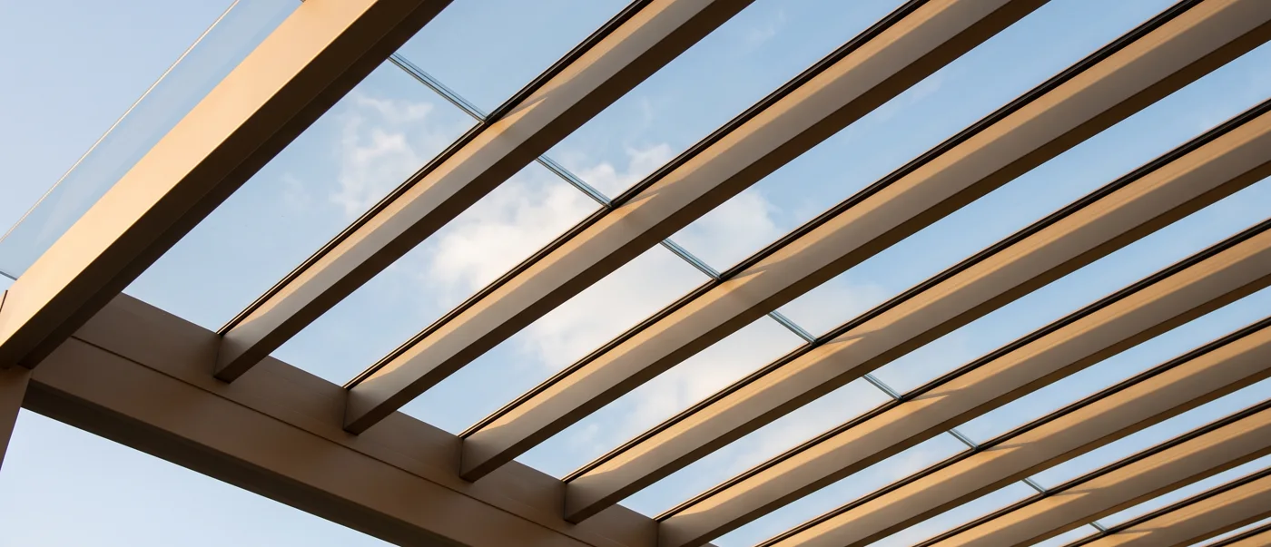 One plane of laminated glass over evenly spaced parallel rafters, sky above, sealed in continuous gaskets