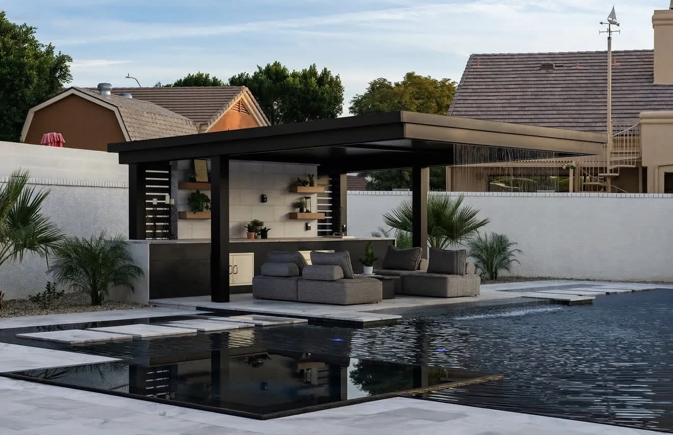 The same black-framed hard top seen from across the pool at dusk, the terrace and planting reading in one line — photograph
