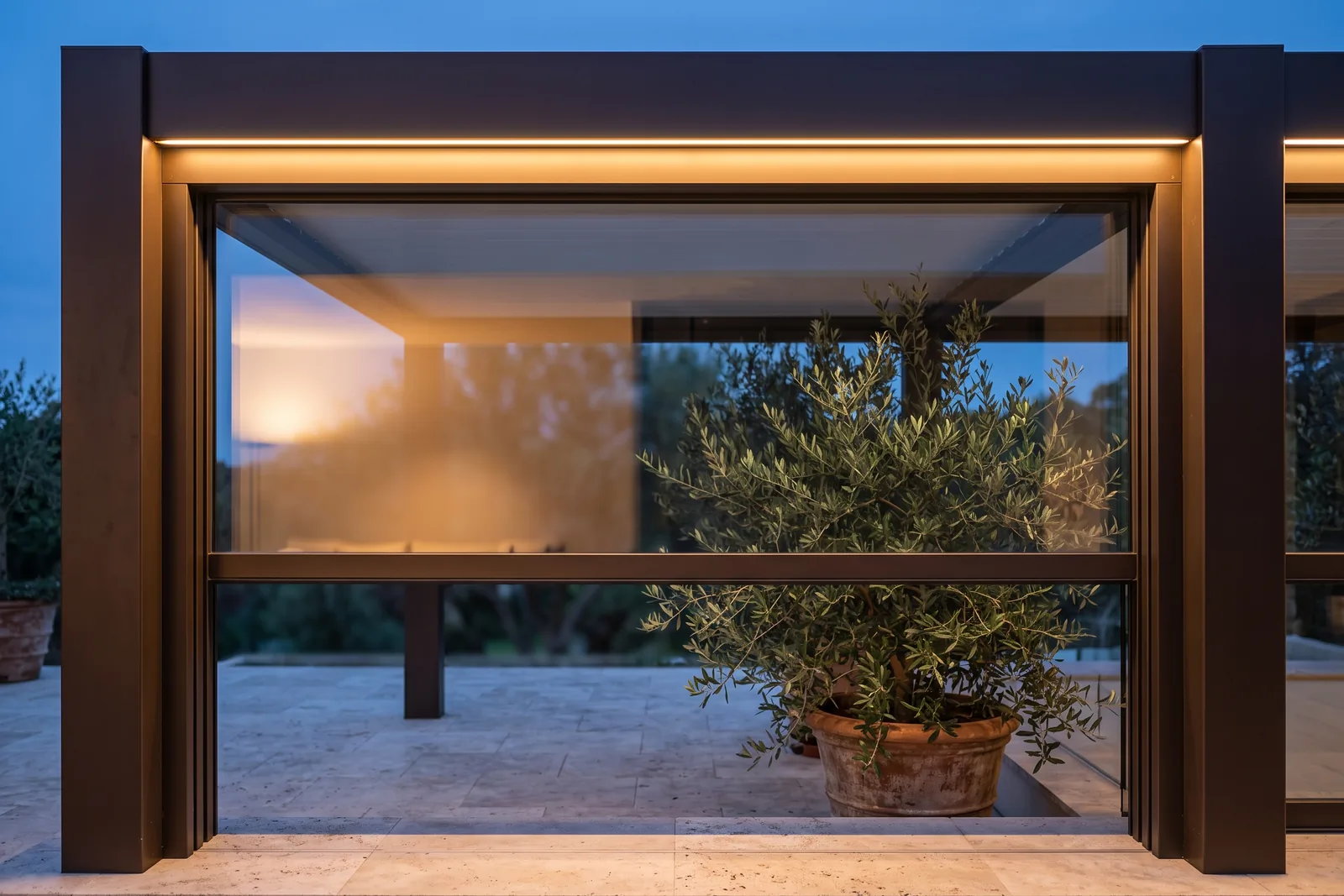 A guillotine glass pane risen halfway in a pergola bay, open air above its top edge